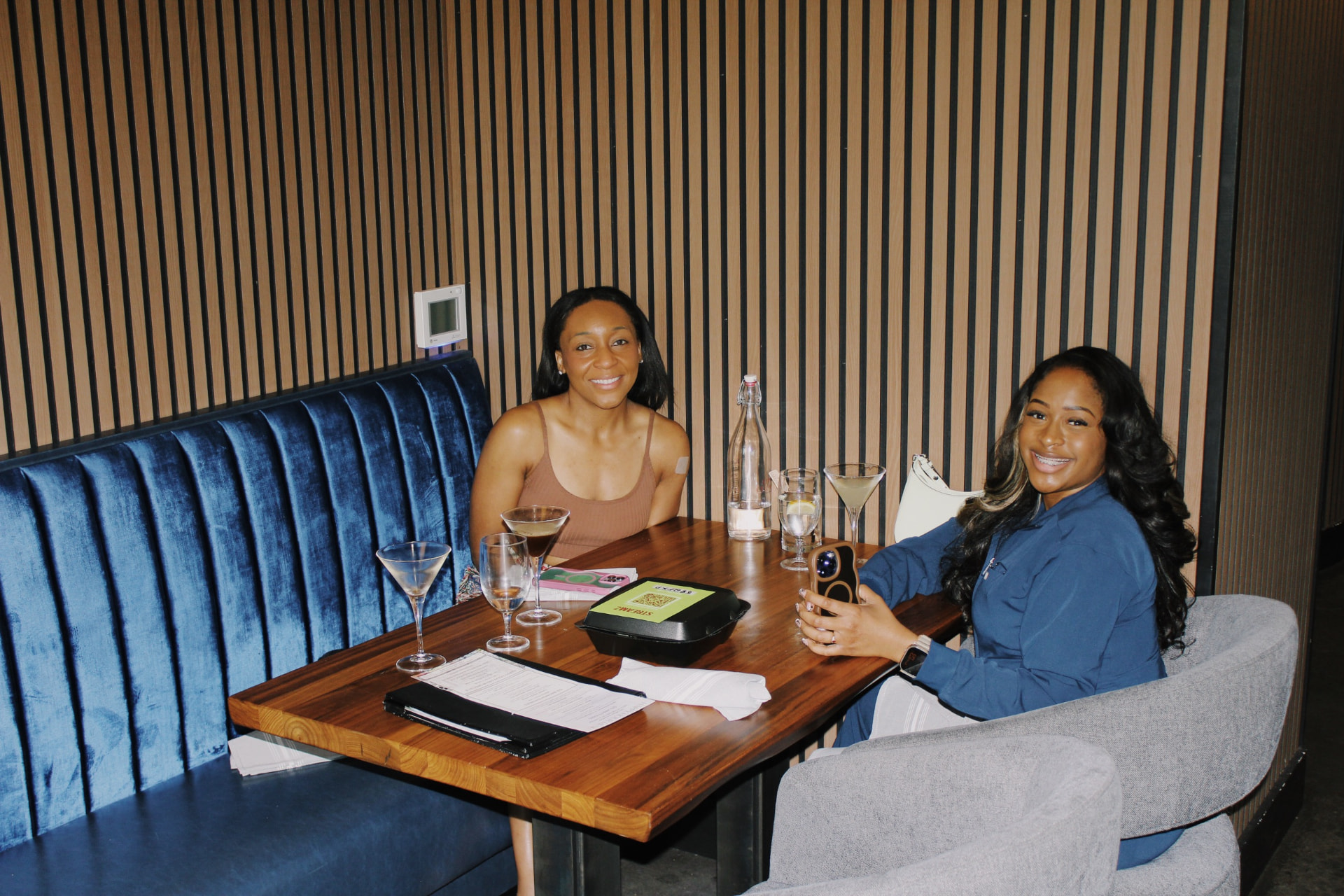 Two guests smiling in a booth with drinks and a game night sign