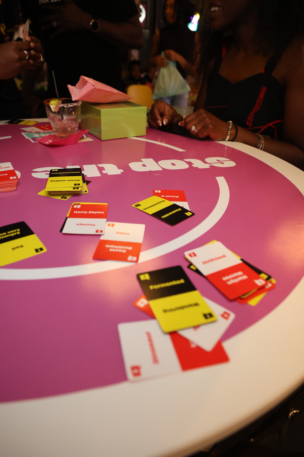 Colorful party cards spread across a pink game table